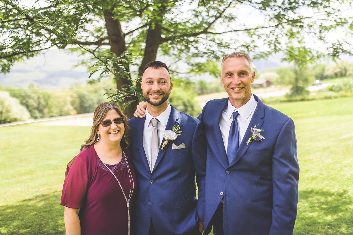 Small group portrait of wedding party members in navy suits outdoors.