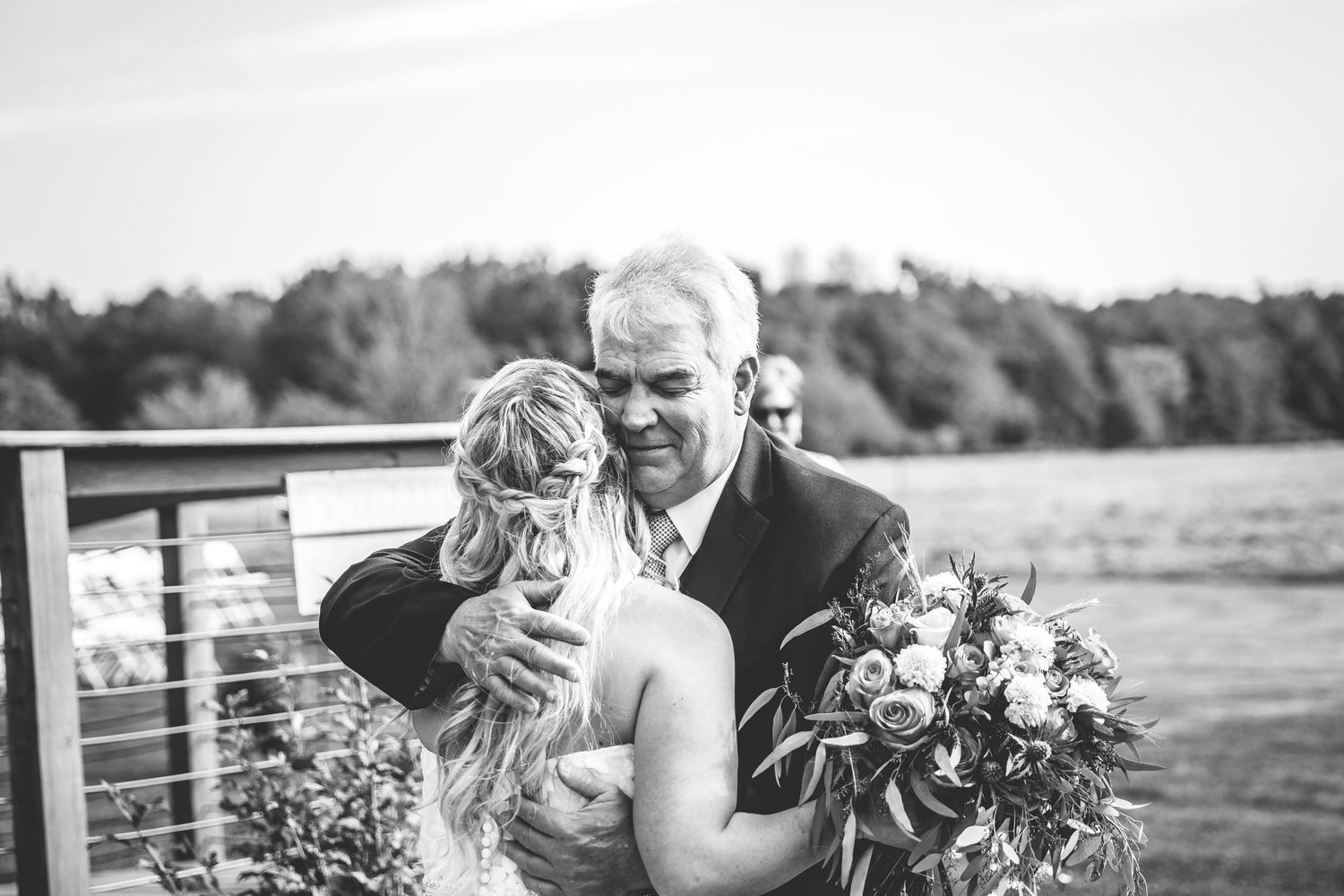 Black and white wedding photo of an intimate moment on a waterfront deck.