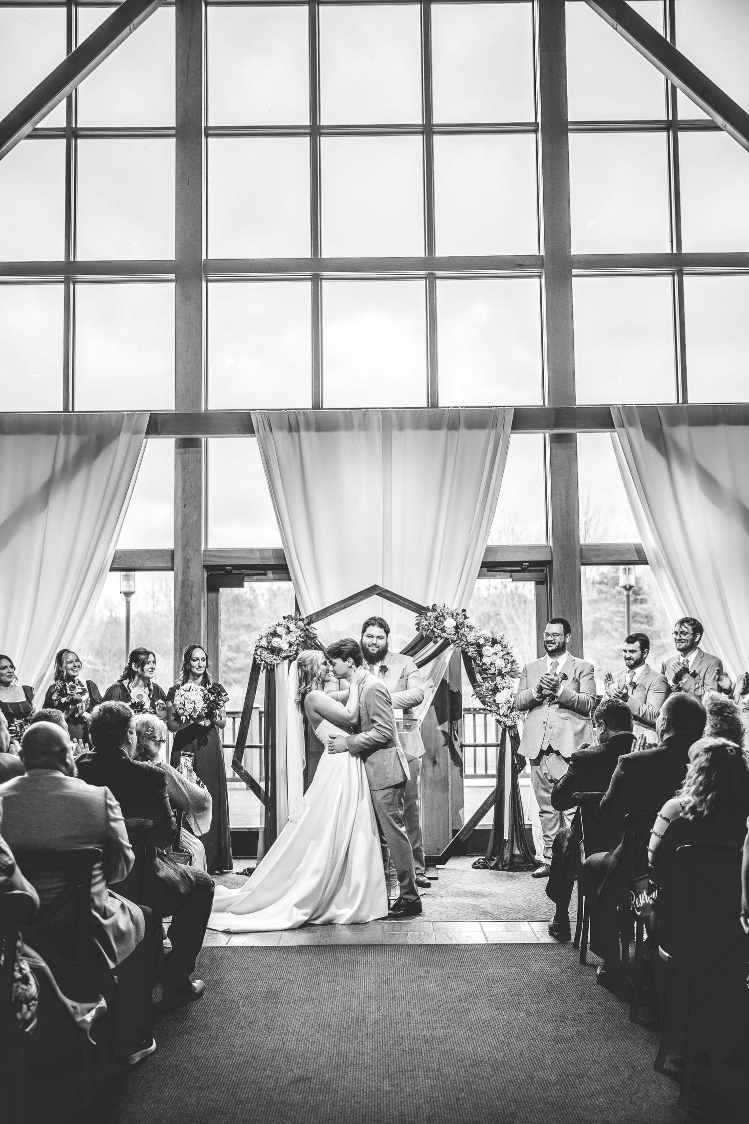 Black and white panoramic view of a wedding ceremony with guests seated in rows.