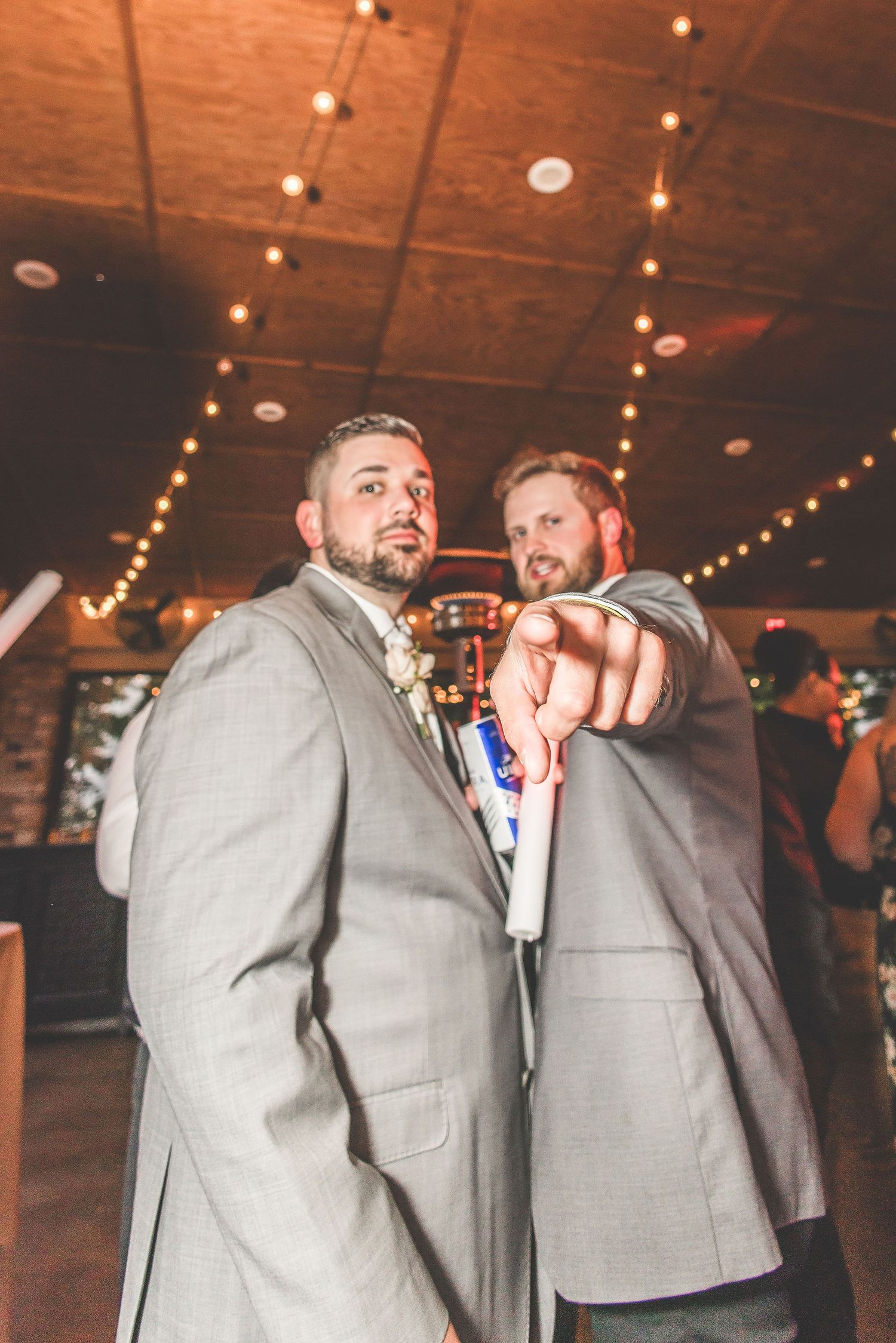 Groomsmen in gray suits sharing playful moments during wedding celebration.