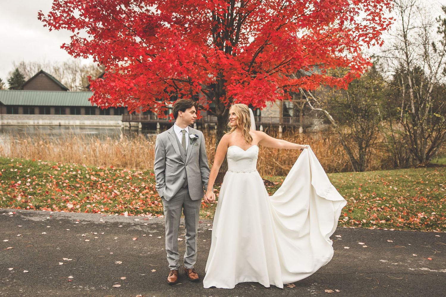Wedding party photos taken beneath vibrant red maple trees during fall season.