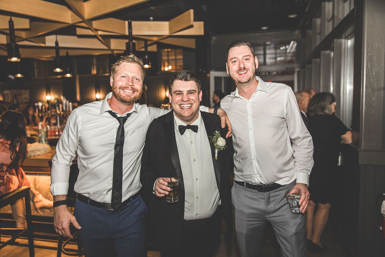 Three guests pose together at an elegant evening event in formal attire.