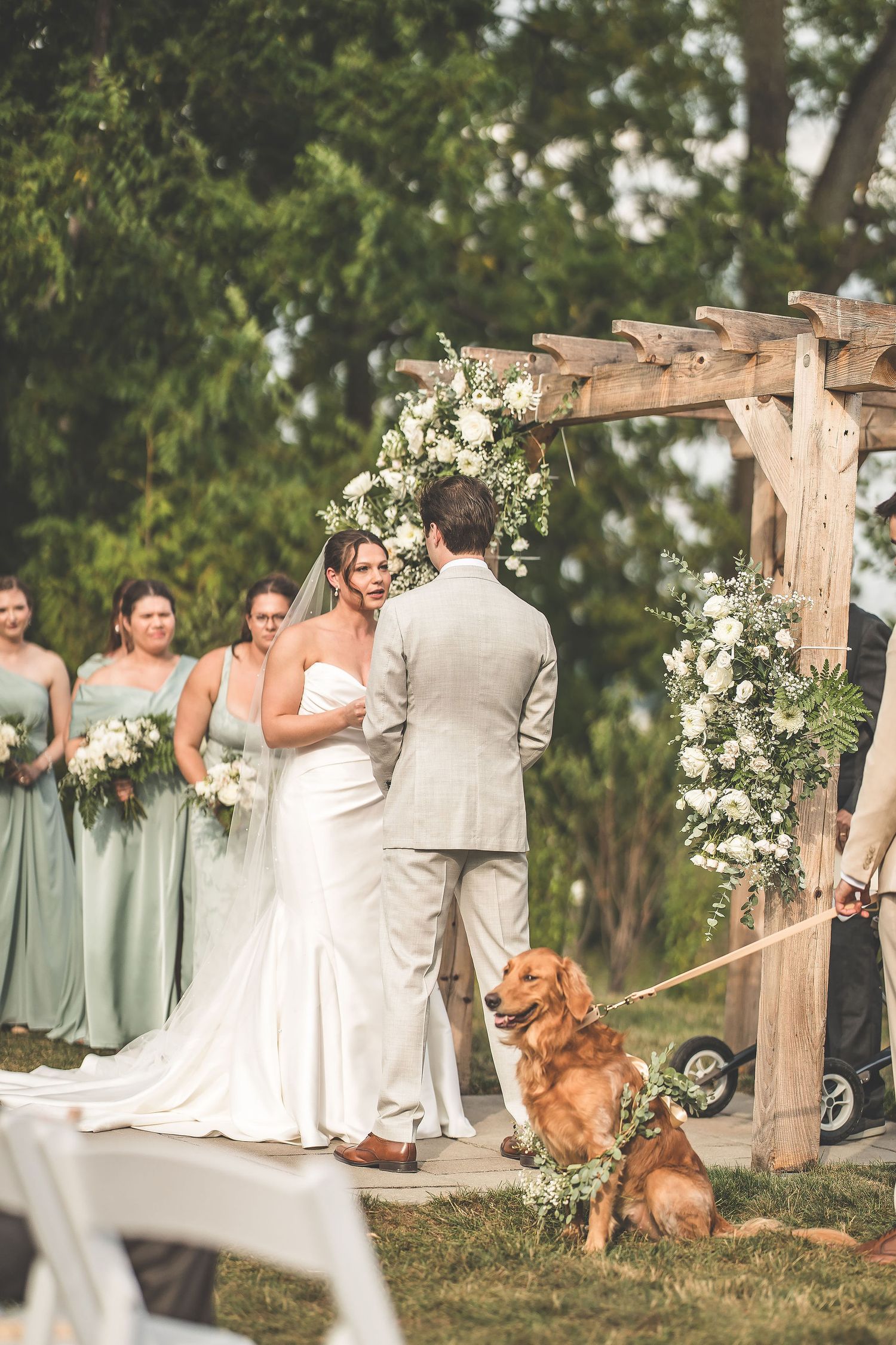 Wedding ceremony under wooden pergola with golden retriever and mint green bridesmaids dresses.