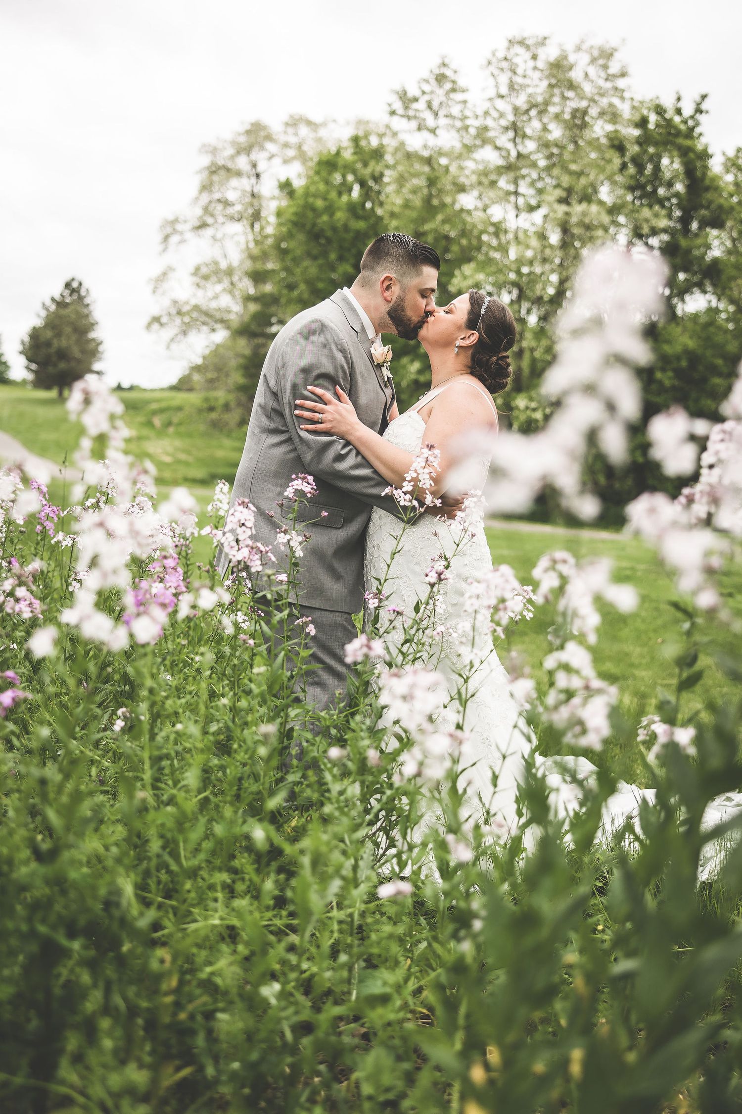 Newlyweds share a romantic moment surrounded by delicate white and purple wildflowers.