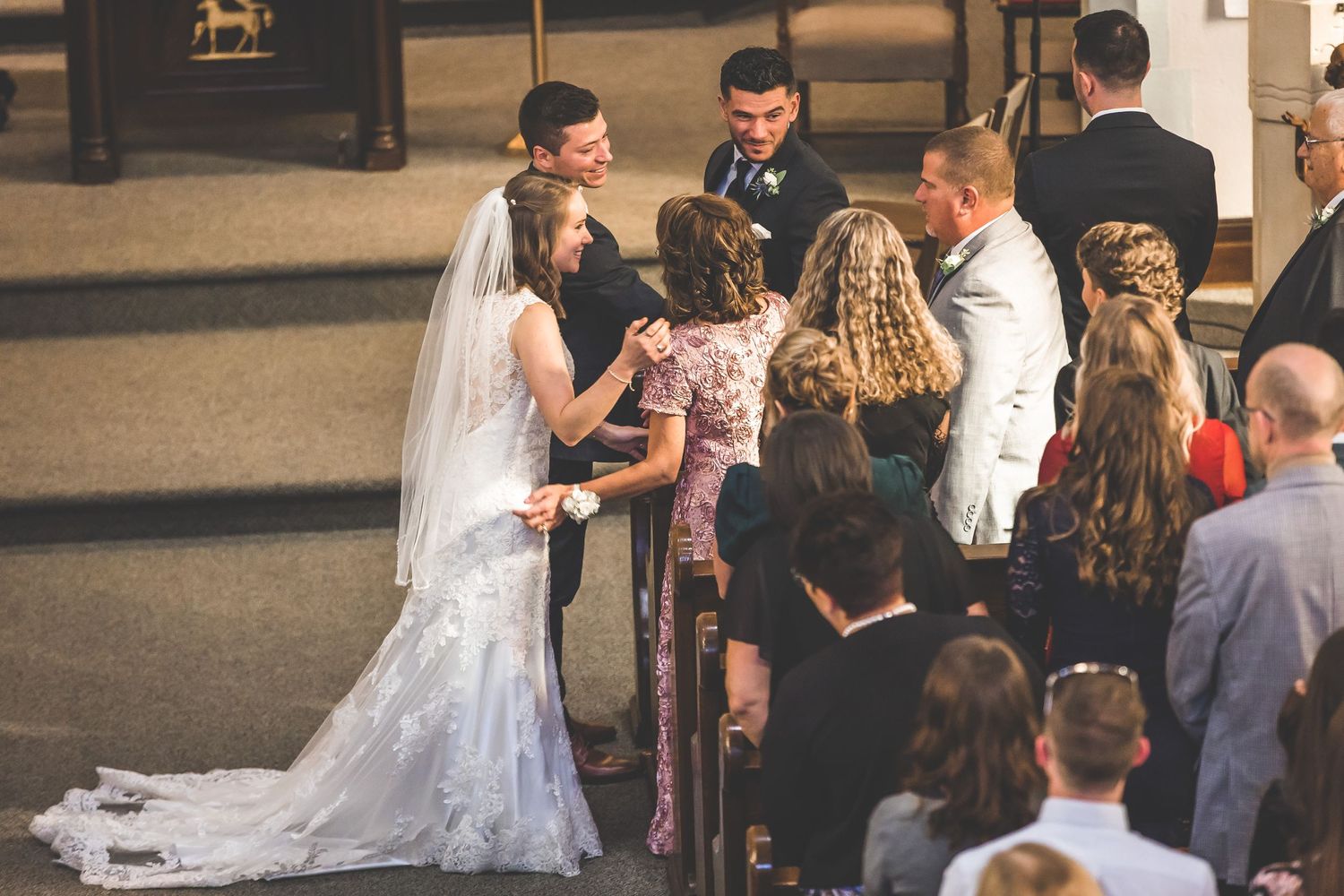 Wedding guests gather in church pews during a ceremony celebration.