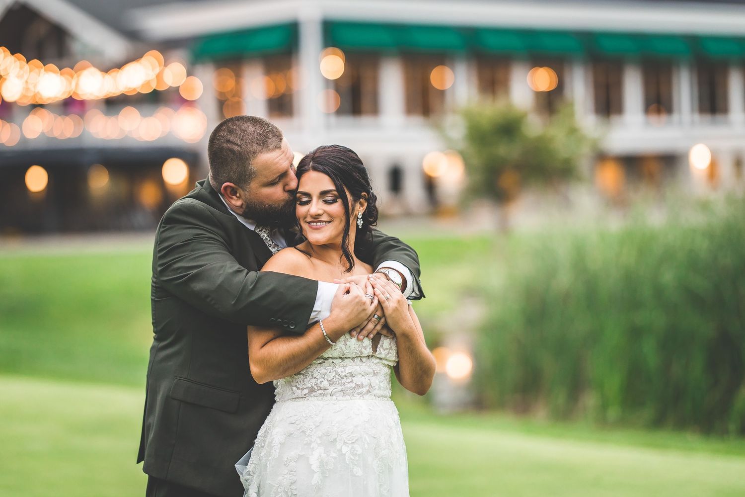 A joyful outdoor wedding moment captured with a couple embracing on a grassy lawn.