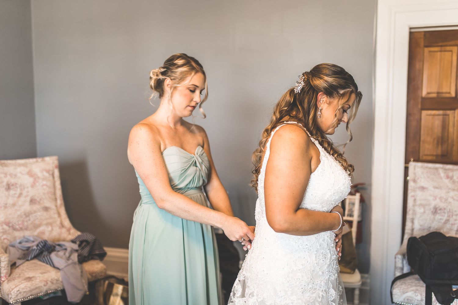 Bridesmaids in matching mint green dresses assisting with wedding preparations.