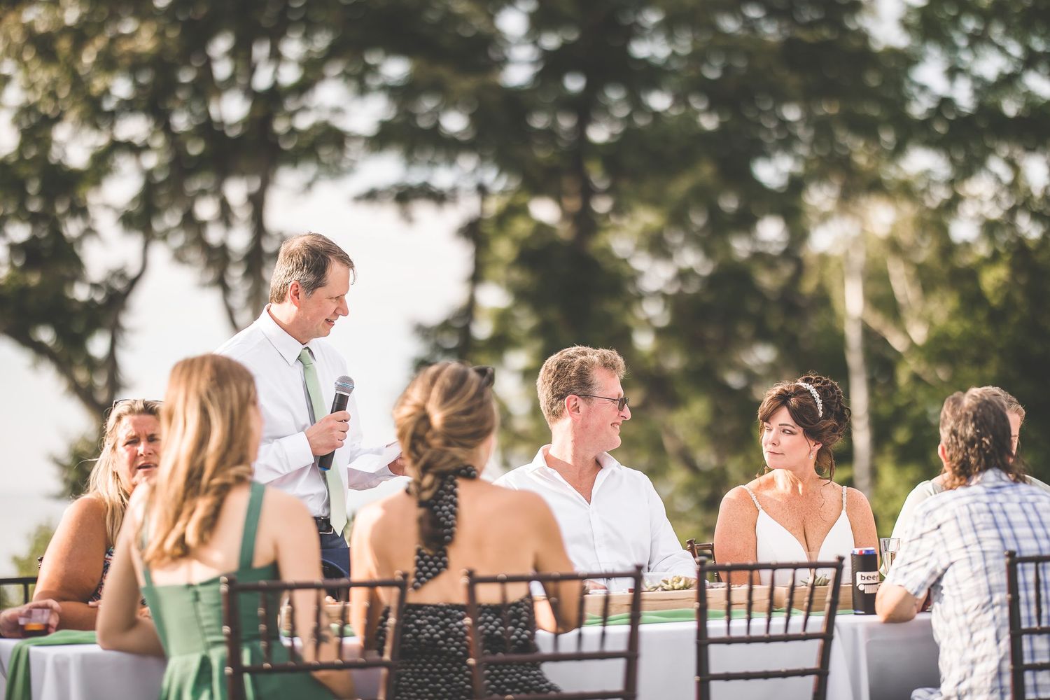Wedding guests enjoying an outdoor reception with natural lighting and garden scenery.
