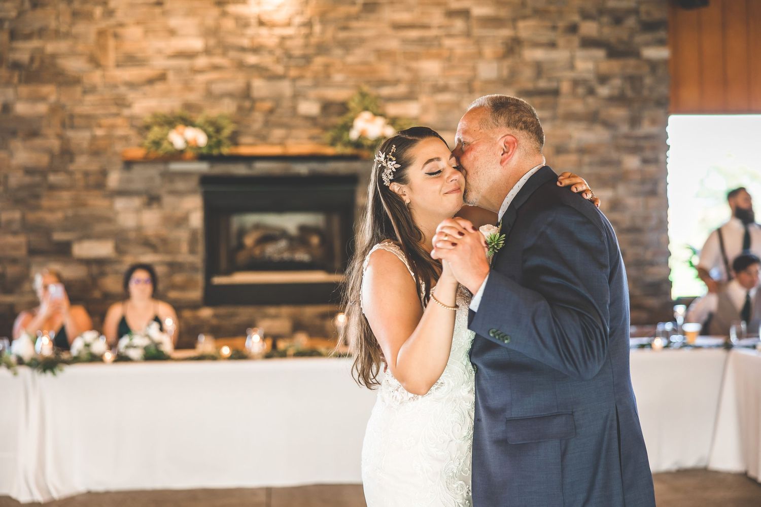 Newlyweds share an intimate dance together at their reception with stone walls in the background.