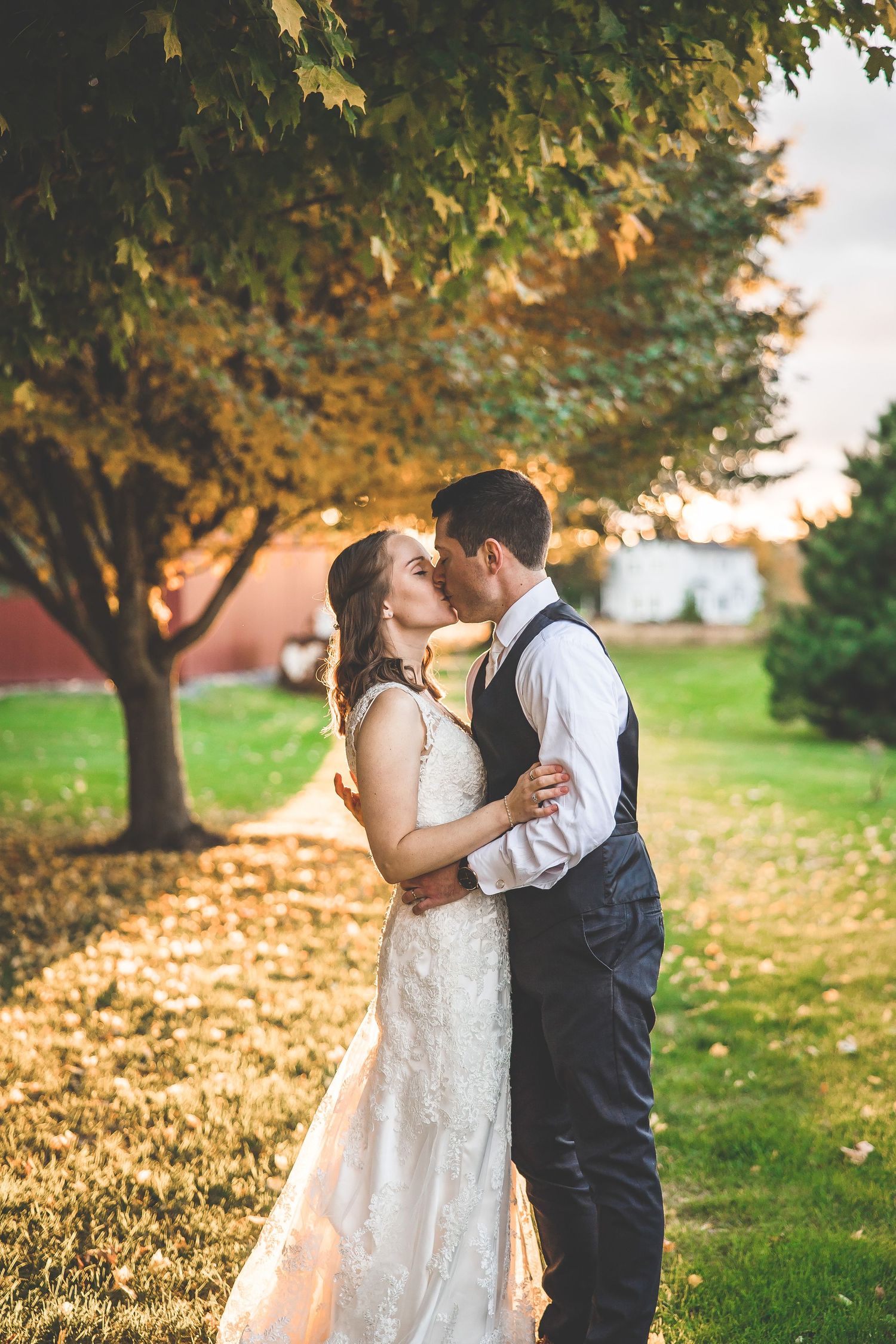 Romantic sunset kiss under fall trees with golden light filtering through.