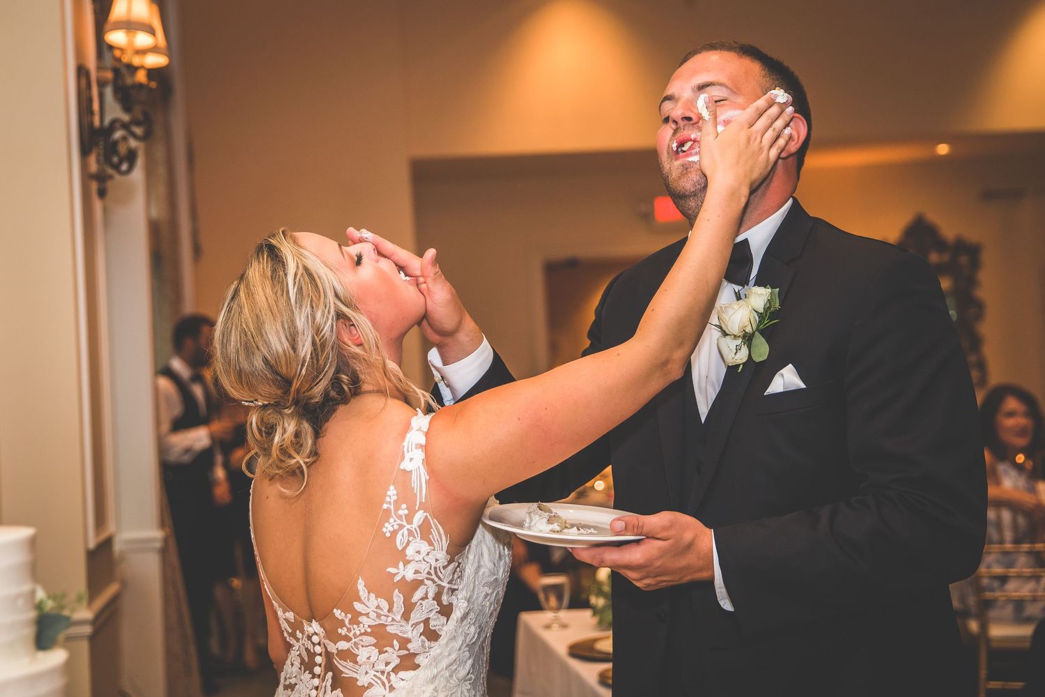 Joyful wedding reception moments with cake sharing between the couple.