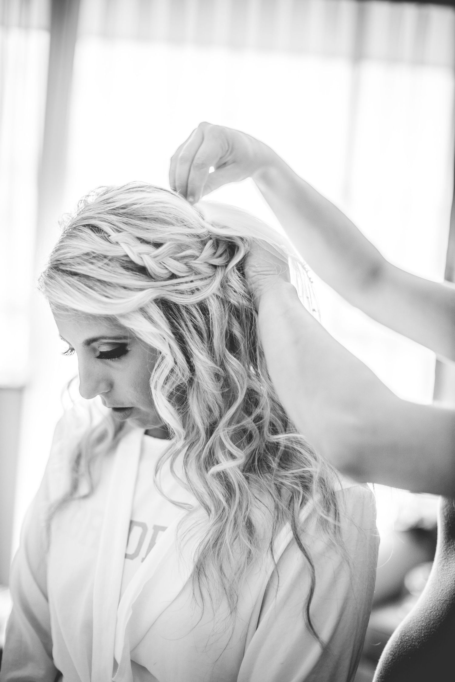 Bride getting her hair styled in soft natural window light.
