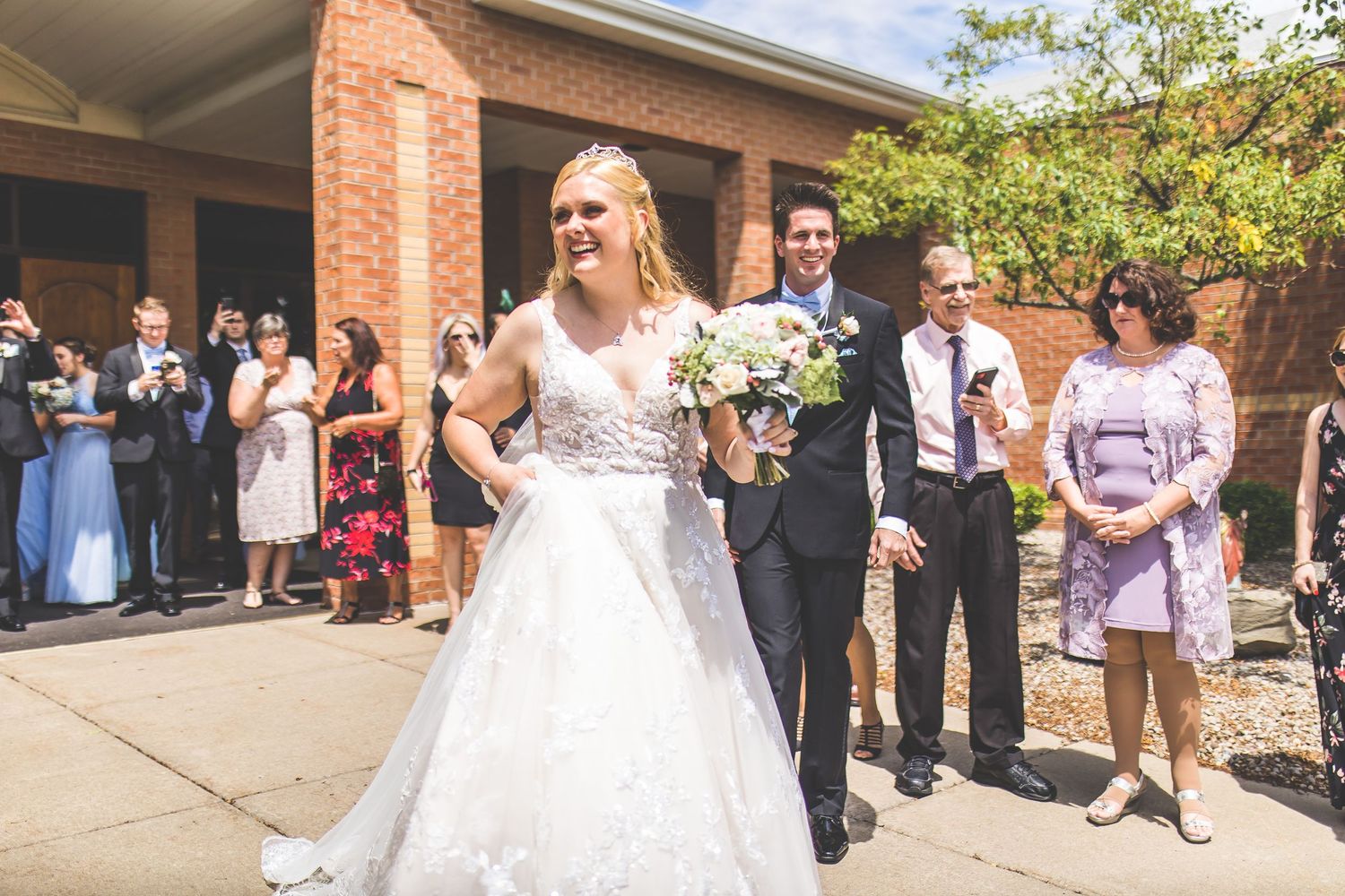 Wedding celebration outside brick church entrance with guests looking on.