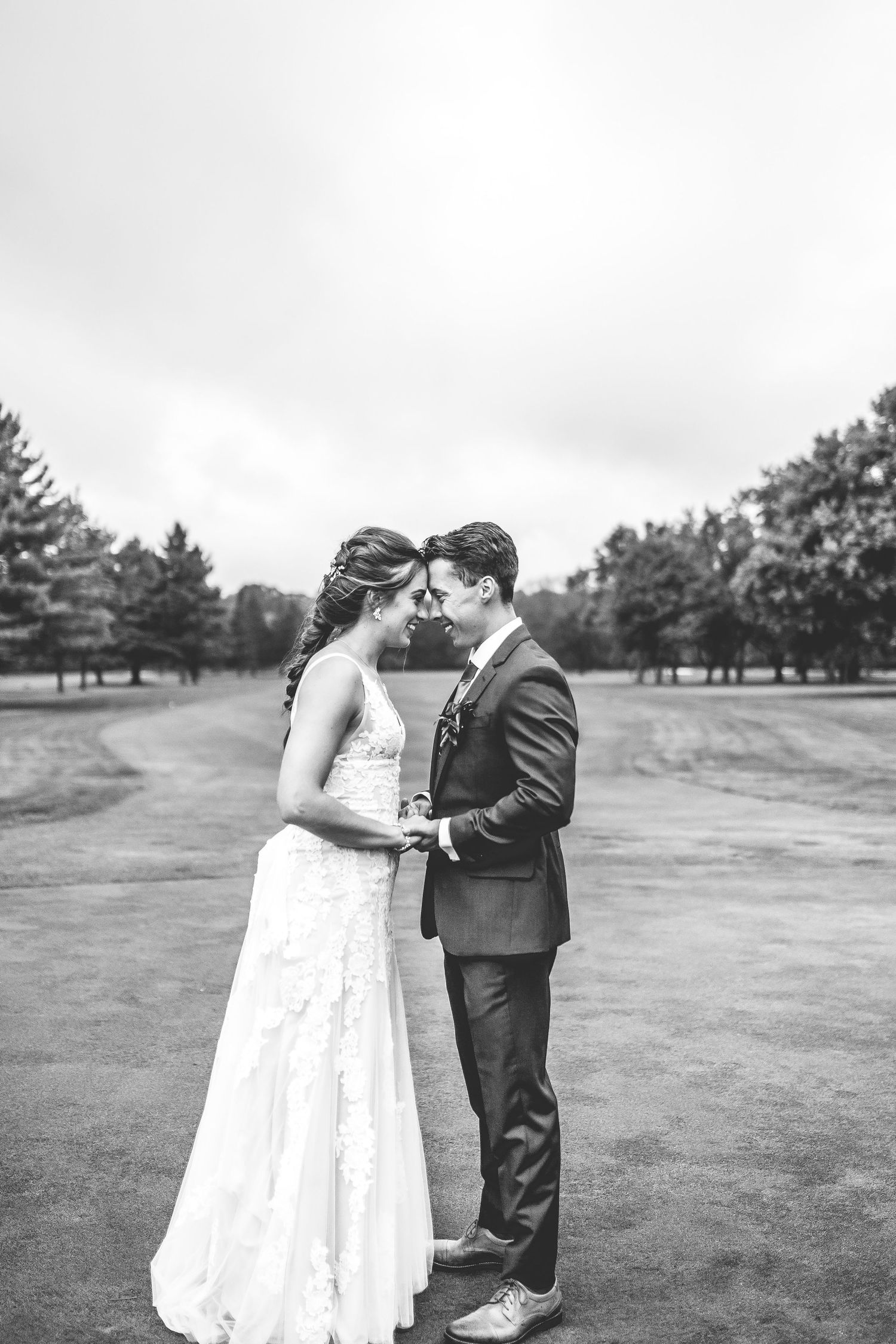 Black and white portrait of newlyweds sharing intimate moments on a golf course.