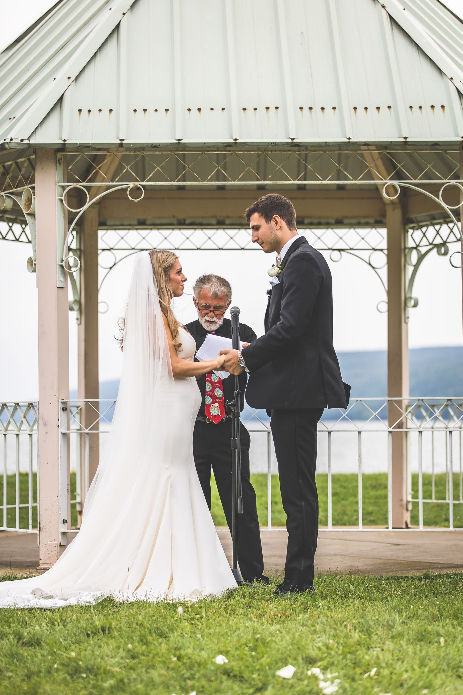 Intimate wedding ceremony taking place inside white gazebo with mountain views.