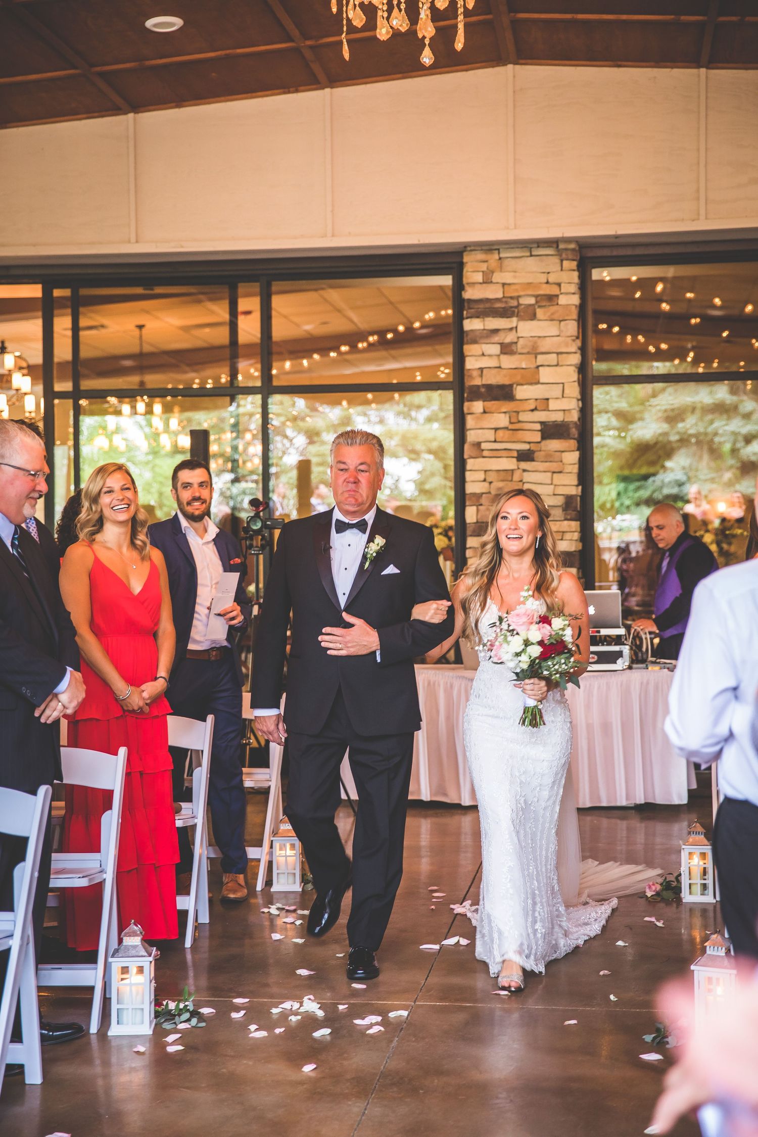 Wedding reception in progress with guests walking through an elegant venue decorated with string lights.