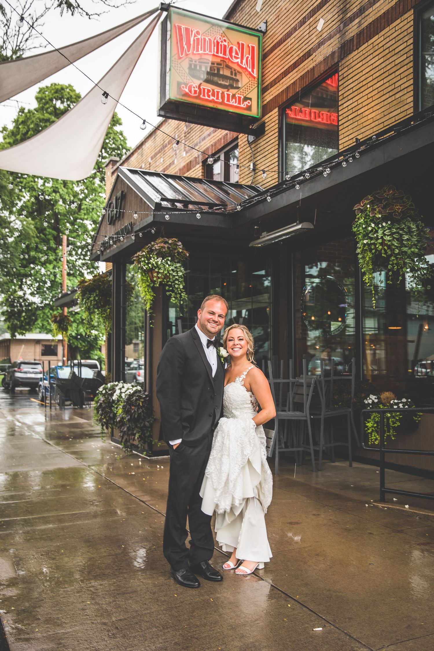 Couple walking together on a rainy day outside a restaurant with brick exterior and awnings.