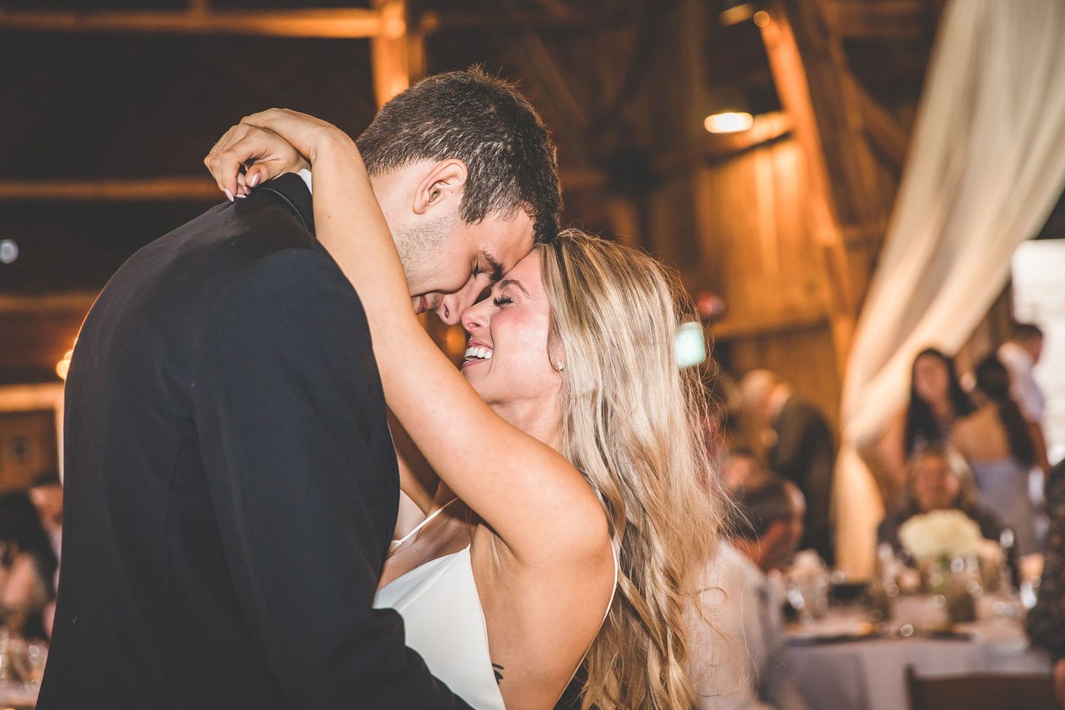Intimate dance moment captured during wedding reception in rustic barn setting.