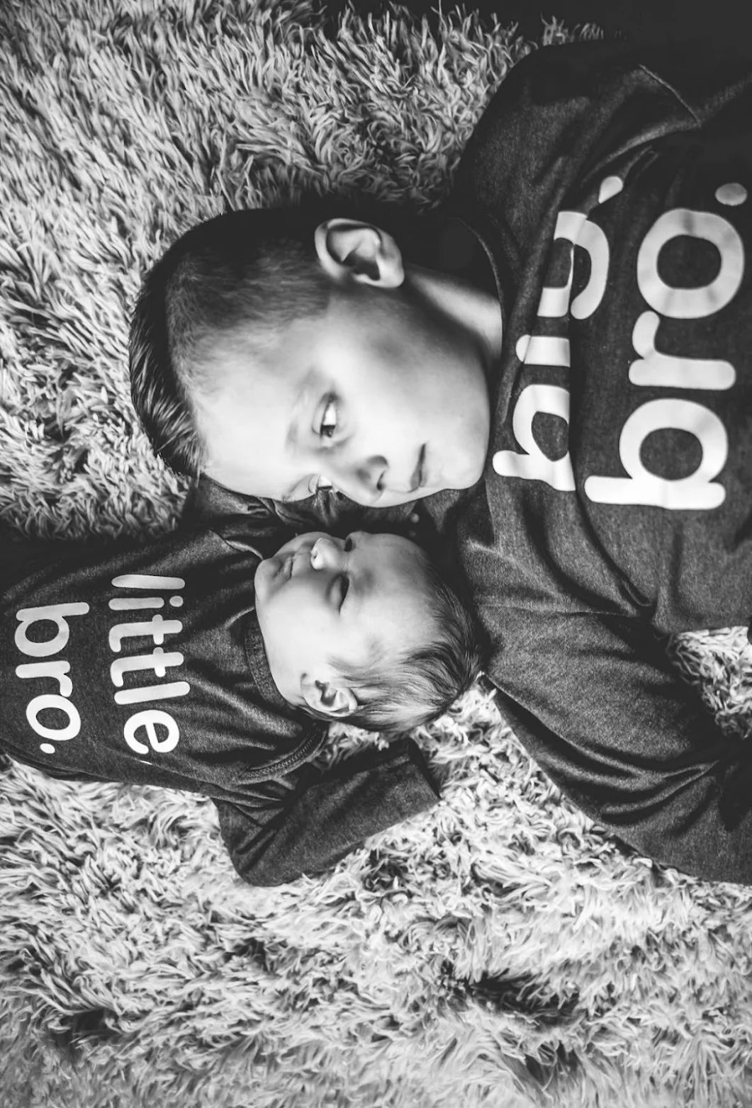 Black and white portrait of people lying on grass wearing dark clothing.