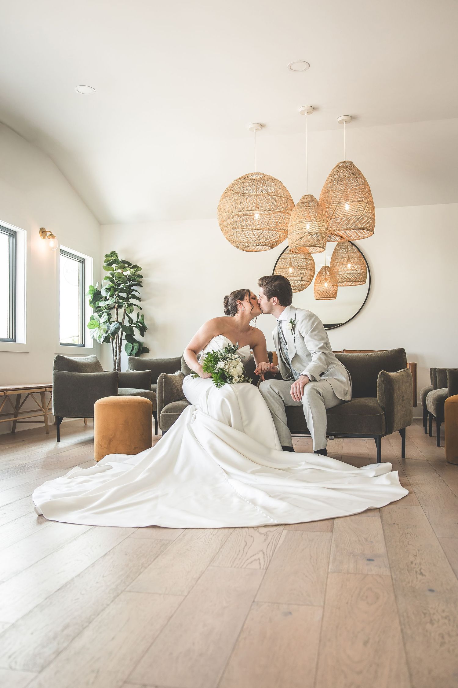 Couple shares intimate moment on couch under woven pendant lights in modern room.