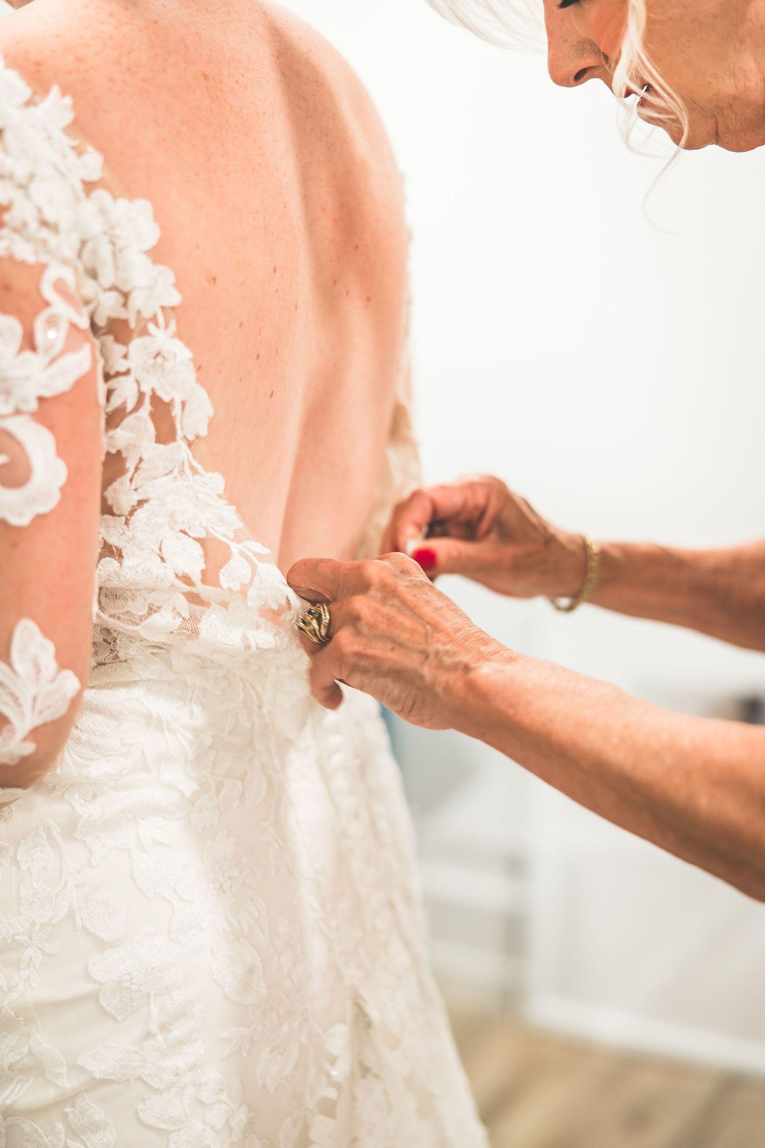Close-up detail of white lace wedding dress being adjusted.