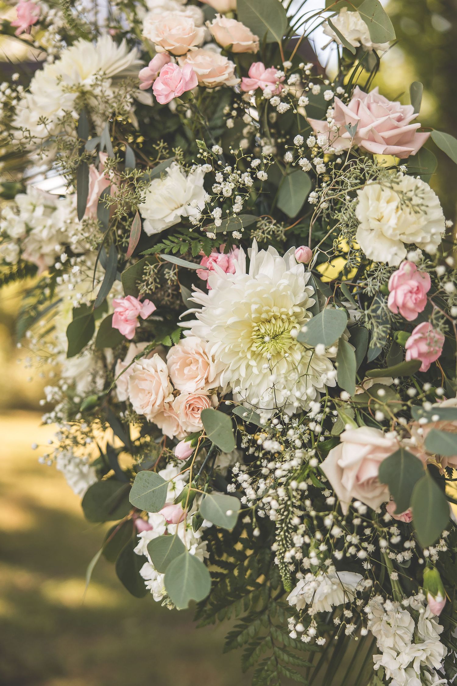 Elegant floral arrangements with pink and white flowers, baby's breath, and greenery for a wedding ceremony.