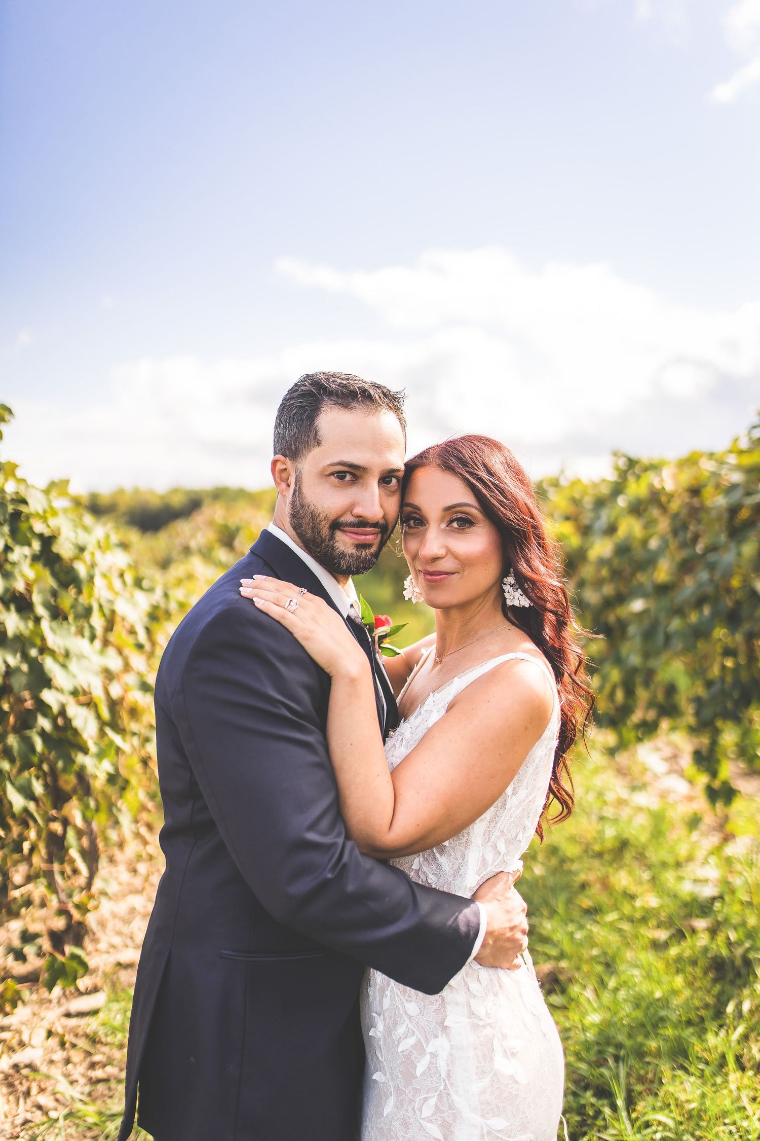 A tender embrace captured between newlyweds in a sunlit vineyard setting.