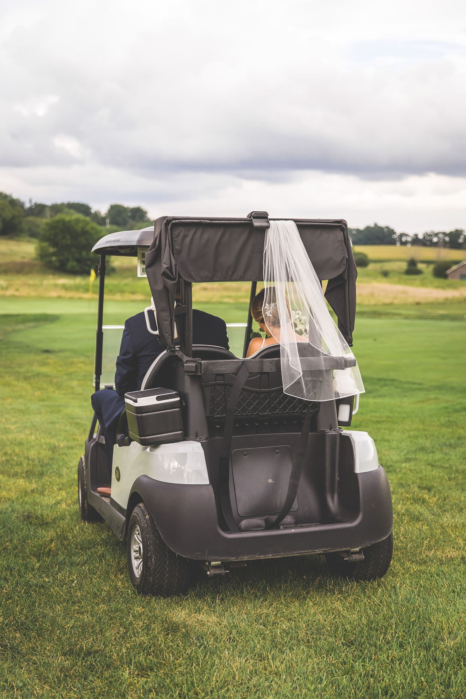 Golf cart decorated for wedding transportation parked on lush green grass.