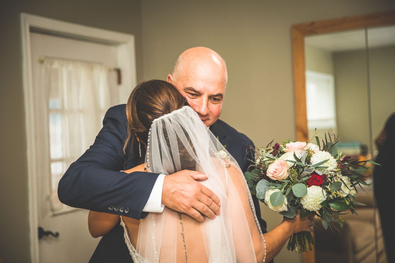 Emotional first look moment between bride and family members in a warmly lit indoor setting.