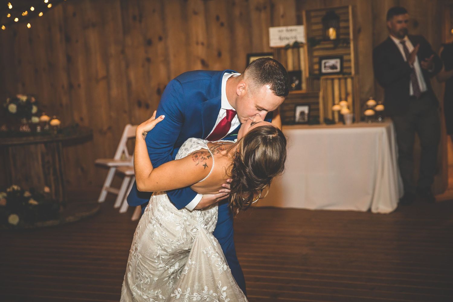 Wedding reception dancing captured in rustic barn venue with string lights and wooden details.