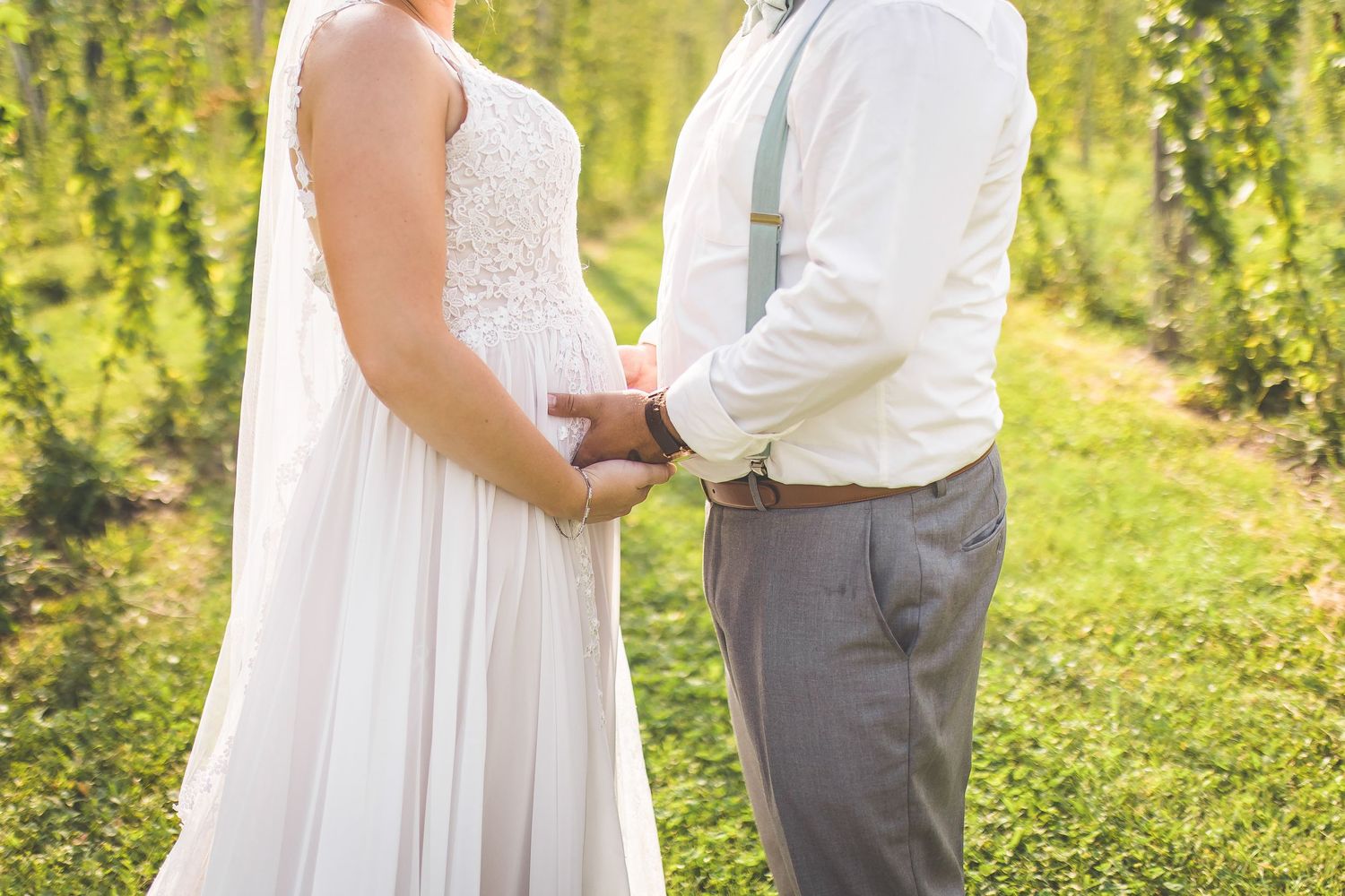 Candid wedding moments captured in a scenic hop field during golden hour.