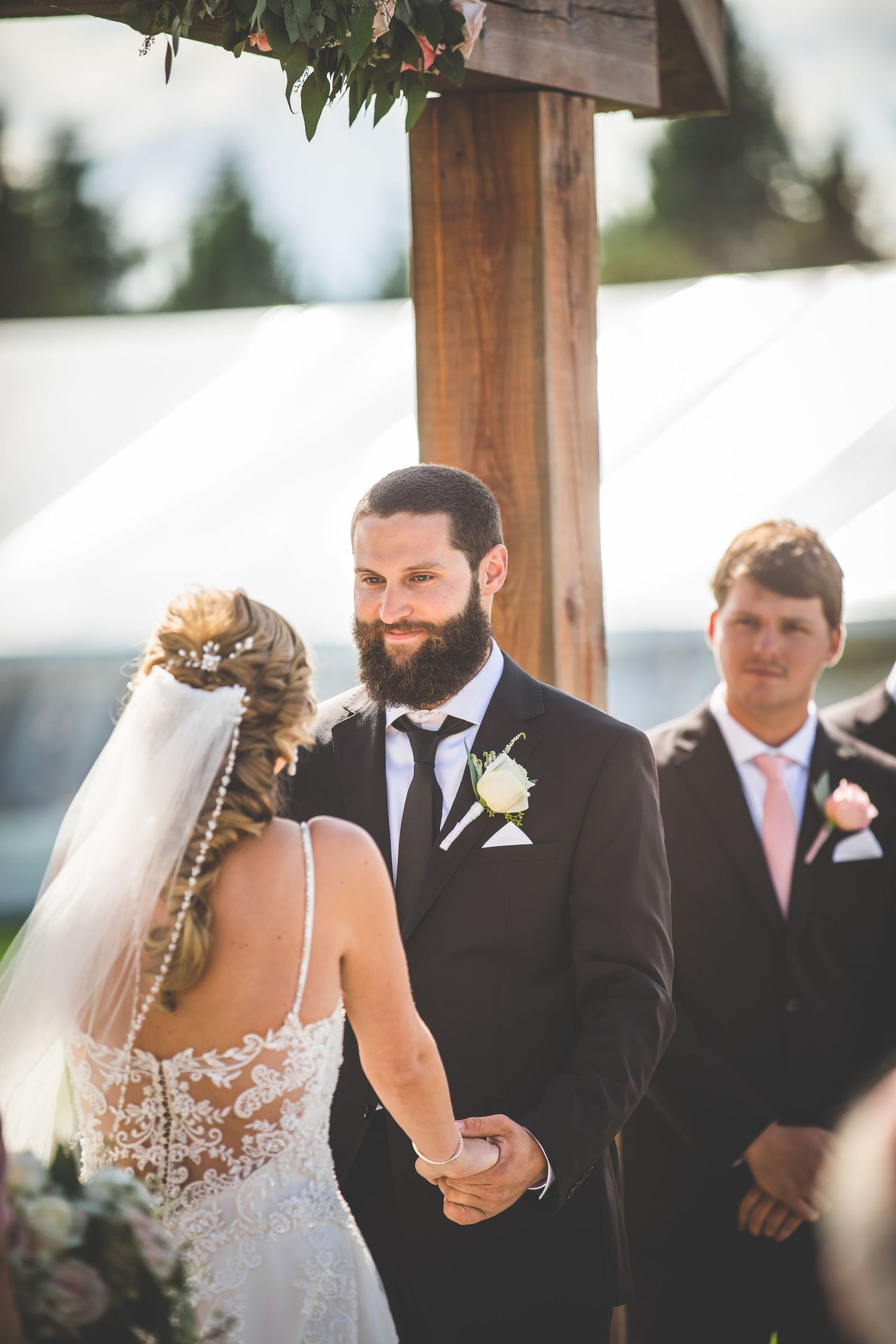 A romantic wedding ceremony moment under a wooden pergola with mountain views.