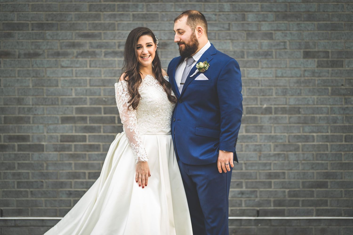 Wedding portraits against industrial brick wall showing romantic moments between newlyweds.