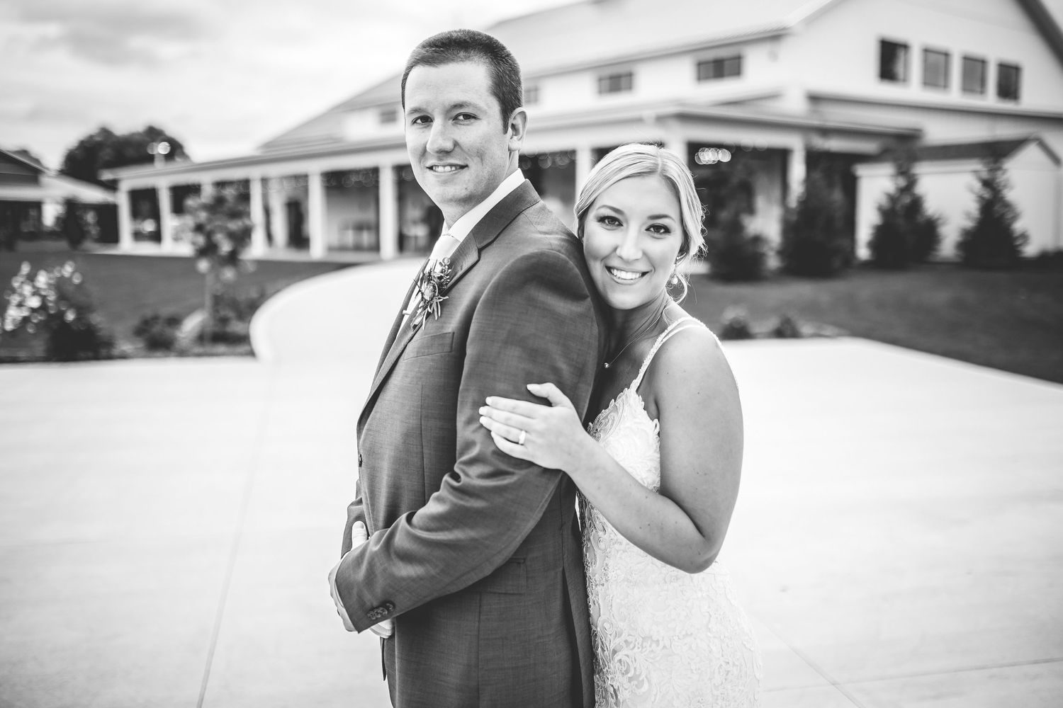 Black and white wedding portraits captured outside a white building.