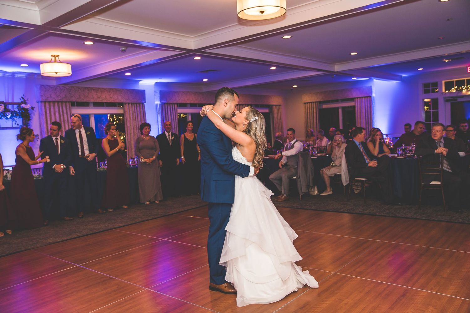 Wedding reception ballroom with couples dancing under blue uplighting.