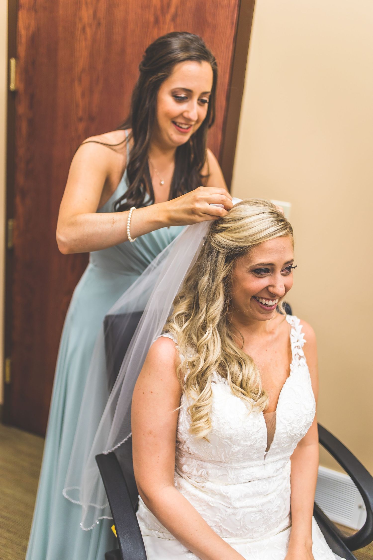 Final wedding preparations show bridesmaids helping style the bride's hair and veil.