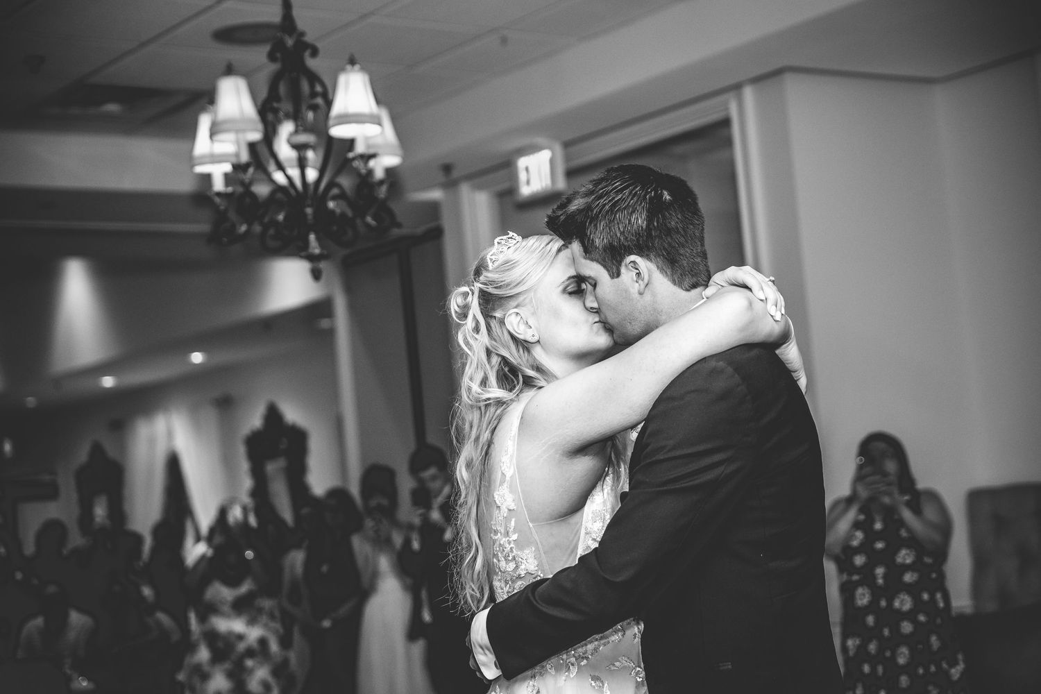 Black and white wedding photo capturing an intimate dance moment in a reception hall.