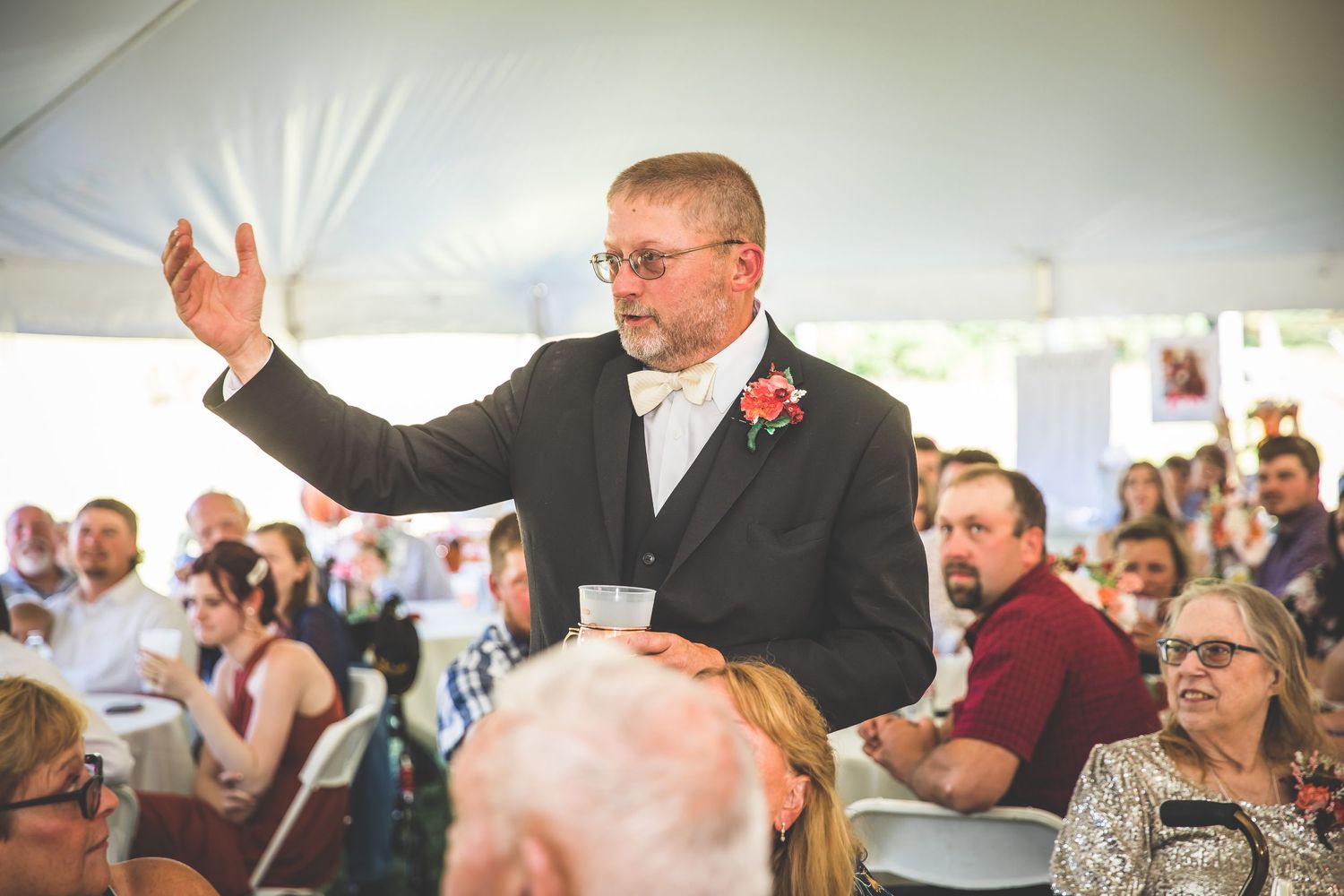 Guests react emotionally during wedding speeches at outdoor tent reception.