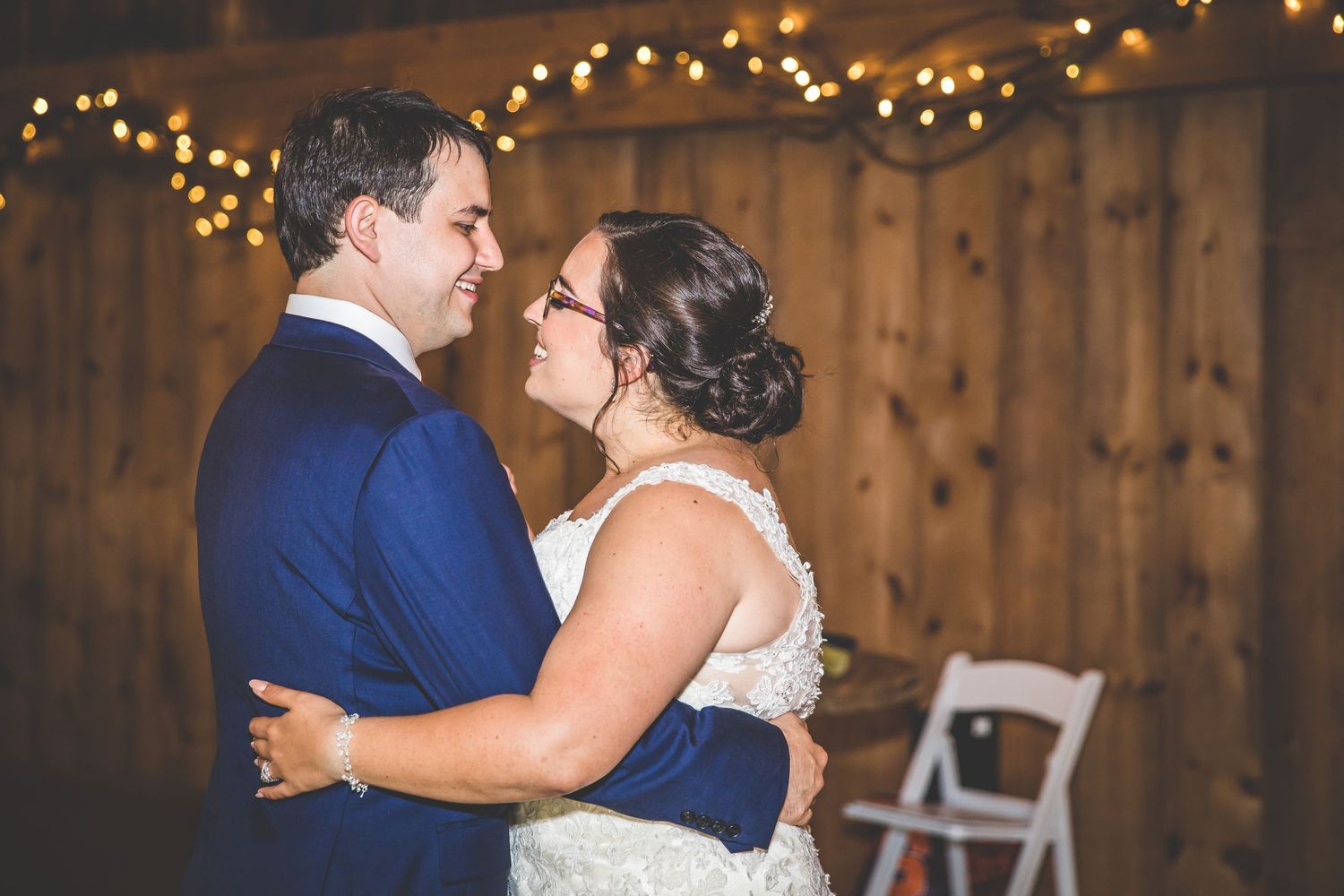 Couples dancing during wedding reception in a warmly lit barn venue.
