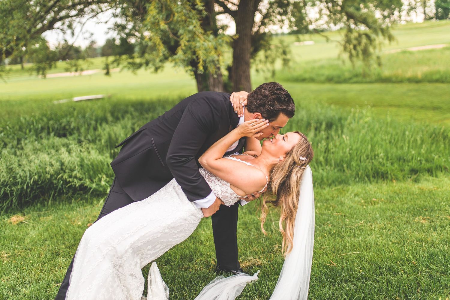 Wedding couple shares romantic moments in sunny outdoor garden setting.