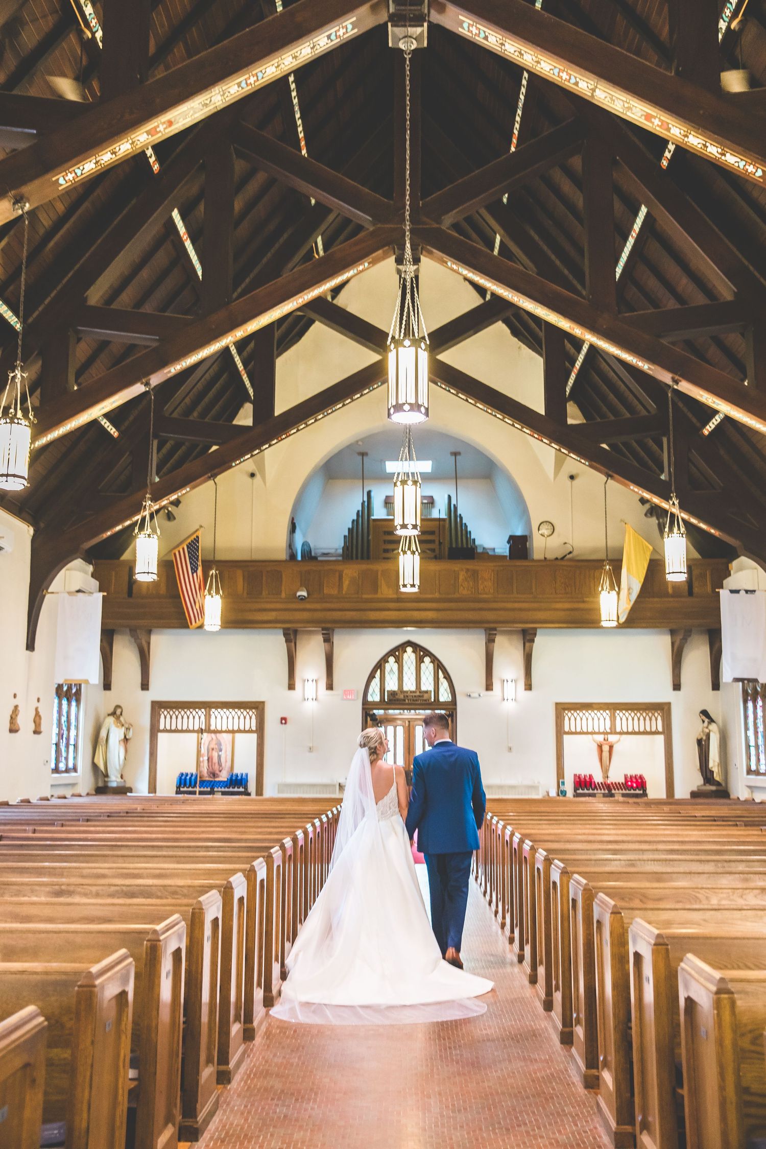 Traditional church interior with wooden pews and vaulted ceiling decorated for wedding ceremony.