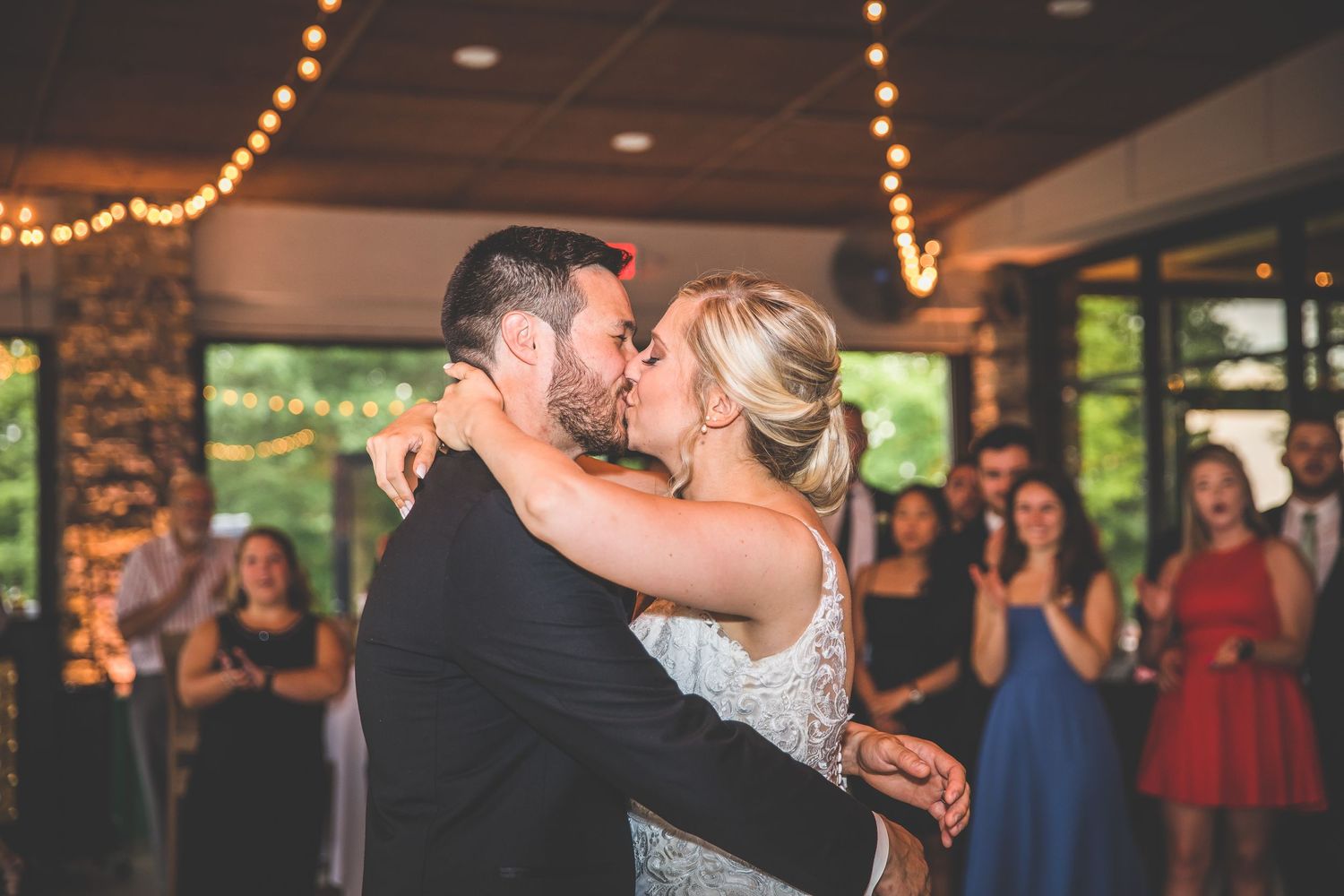 Romantic dance moment captured under warm string lights at wedding reception.