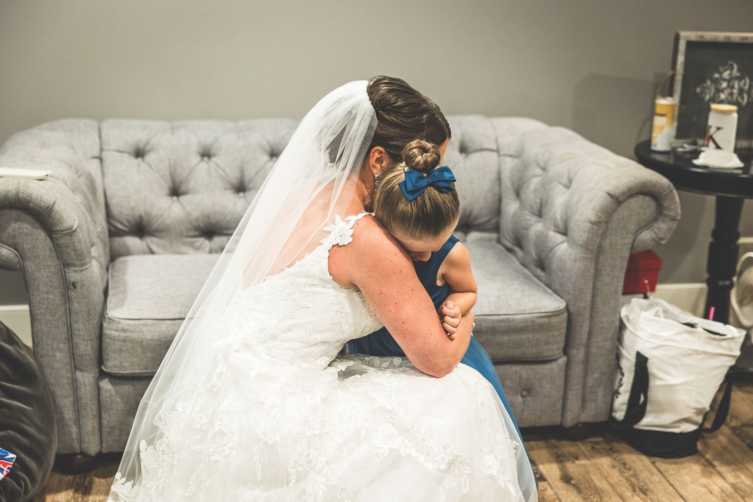 Wedding preparations taking place on a comfortable grey couch in an elegant room.
