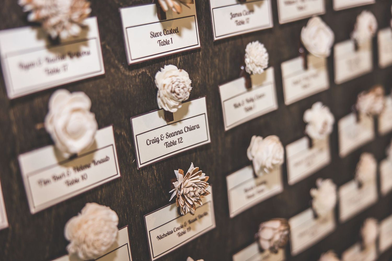 Wedding seating chart display with name cards arranged on dark background.