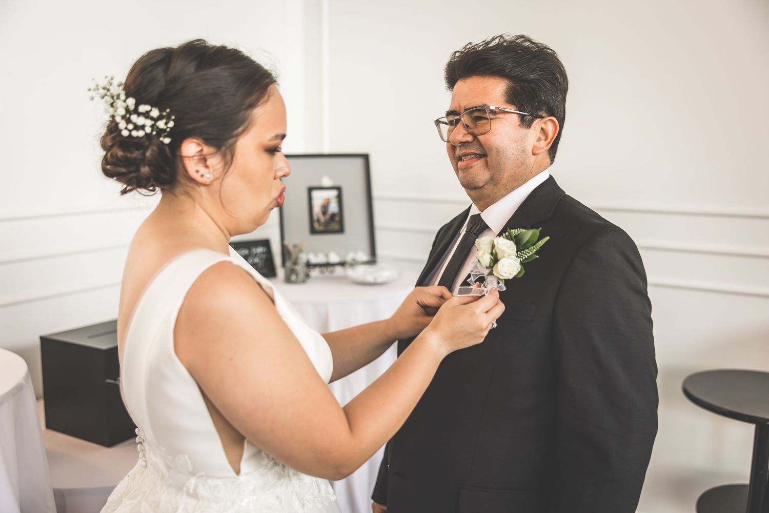 Wedding couple shares tender moments in a bright white interior space.
