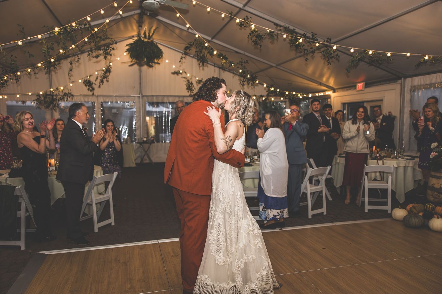 Dance floor at a wedding reception with string lights and greenery decorations overhead.
