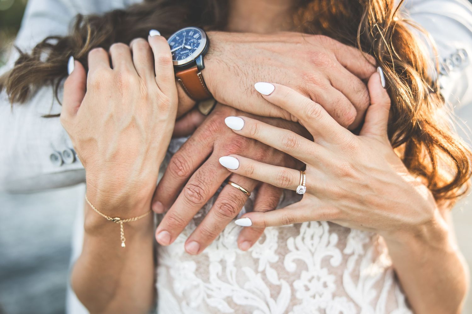 Close-up detail shot of wedding rings and lace dress details.