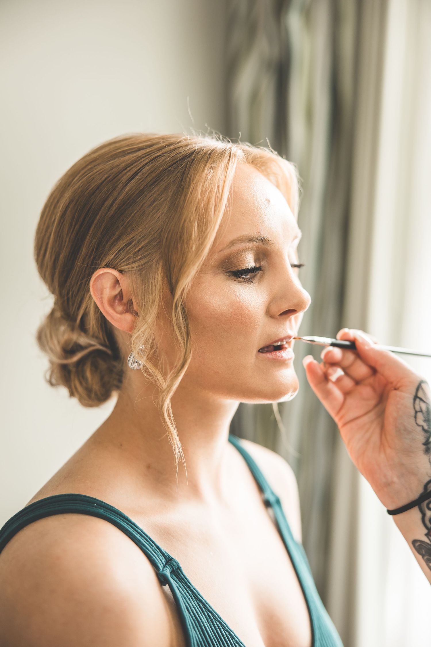 Professional makeup artist applying cosmetics to bride during wedding day preparation.