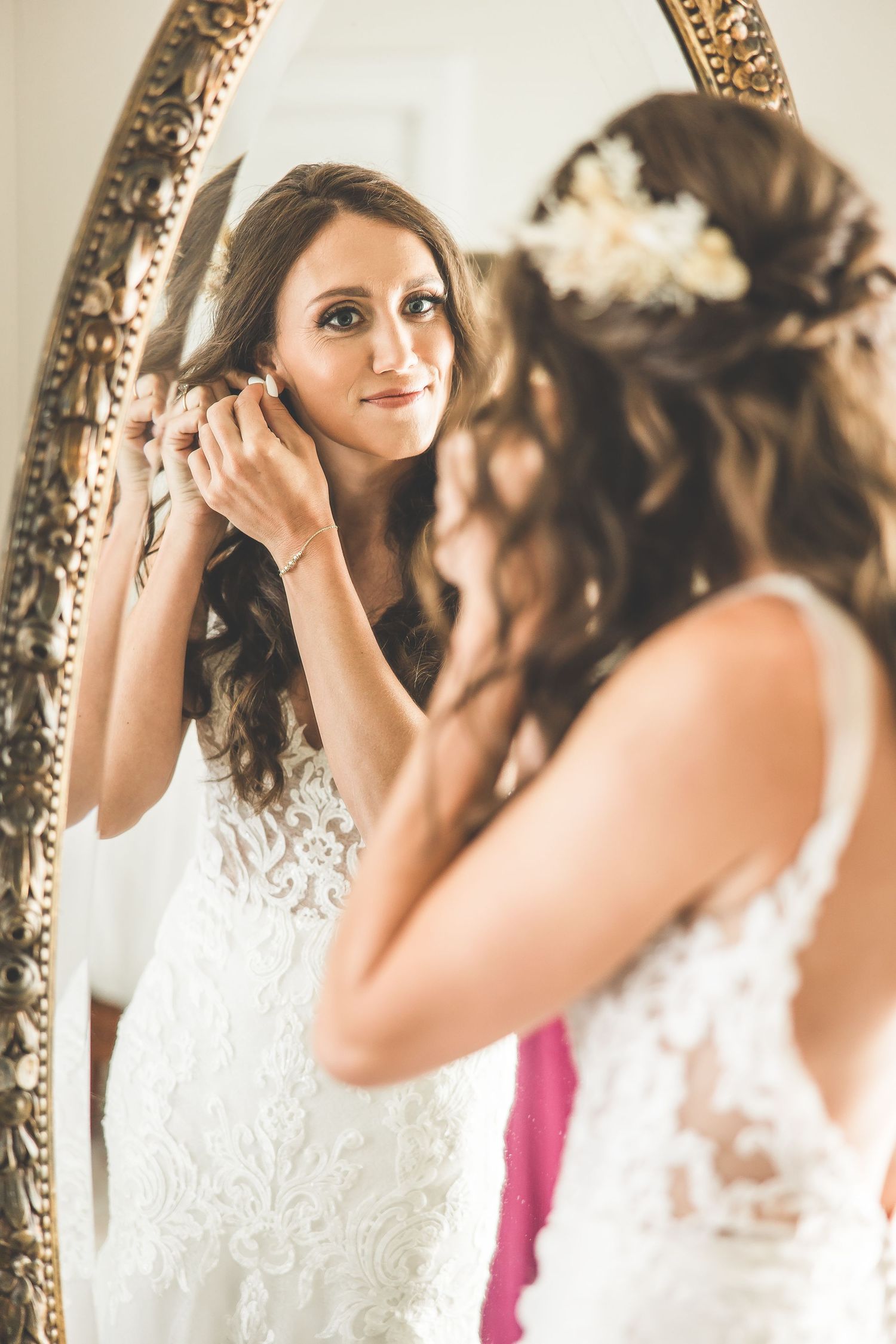 Ornate gold mirror reflects wedding dress details during bridal preparations.