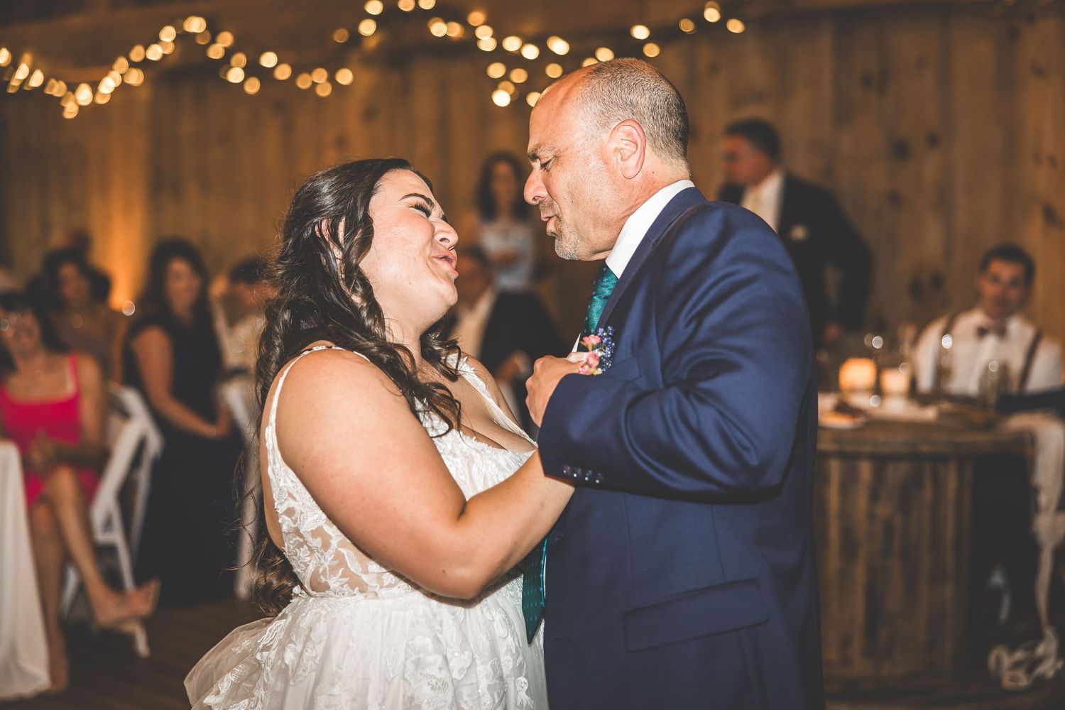 Couples dancing together at rustic barn wedding reception under string lights.
